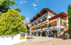 a large white building with orange umbrellas at Small Hotel Sonne in Tirolo
