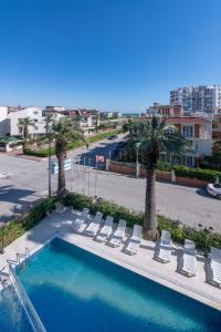 a swimming pool with lounge chairs and palm trees at Theluna City Hotel in Antalya