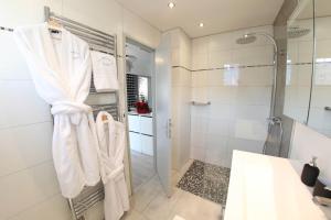 uma casa de banho com um chuveiro e toalhas brancas num cabide em La Maison de Jeanne em Sélestat
