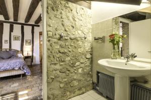 La salle de bains est pourvue d'un lavabo et d'un mur en pierre. dans l'établissement Moulin de Flagy, 