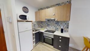 a small kitchen with a white refrigerator and cabinets at Apartamentos Eldorado in Lloret de Mar