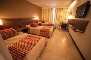 Habitación de hotel con 2 camas y TV de pantalla plana. en Hotel Estilo MB - Villa Carlos Paz en Villa Carlos Paz