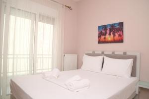 ein Schlafzimmer mit einem weißen Bett mit zwei Handtüchern darauf in der Unterkunft R&K Suites in Keramotí