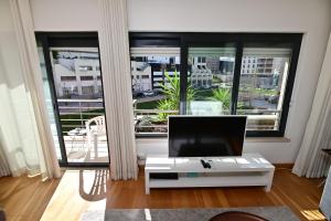 ein Wohnzimmer mit einem TV und einem großen Fenster in der Unterkunft Columbano Garden, Family Apartment in Lissabon