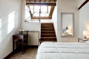 una camera con letto, scrivania e scala di Casa della Fonte - Self check-in a San Quirico dʼOrcia