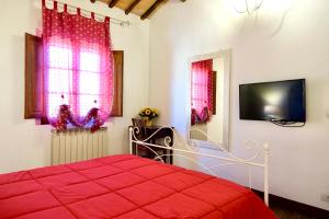 um quarto com uma cama vermelha e uma televisão em Casa della Fonte - Self check-in em San Quirico dʼOrcia