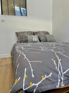 Una cama con un edredón gris con árboles. en Joli appartement au coeur de ville, en Château-Thierry