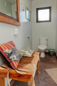 a bathroom with a bench and a mirror and a toilet at Tana Safaris Bush Camp in Otjiwarongo