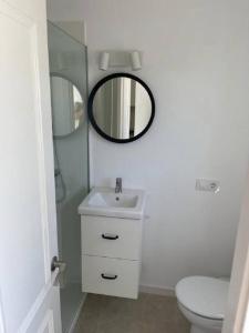 uma casa de banho branca com um lavatório e um espelho em Apartamento CastellSol 102 em Arenal d'en Castell