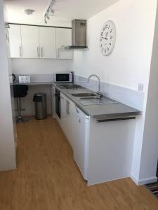 una cocina con fregadero y un reloj en la pared en Old Picture House, en Seaton