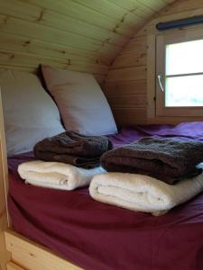 - un lit dans une cabane en bois avec des serviettes dans l'établissement Le Tonneau Bourguignon, à Saint-Léger-sur-Dheune