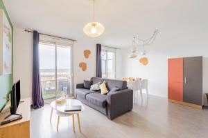 sala de estar con sofá y mesa en Appart'Hotel Versailles Saint Cyr l'Ecole - Gare SNCF RER, en Saint-Cyr-lʼÉcole