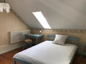 Schlafzimmer mit einem Bett, einem Schreibtisch und einem Dachfenster in der Unterkunft Hôtel Von Bergen in La Sagne