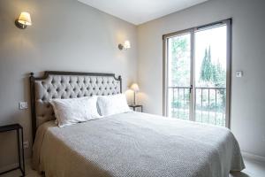 a white bedroom with a large bed and a window at La Maison de l'Yle - Villa avec piscine in L'Isle-sur-la-Sorgue
