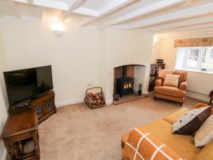 a living room with a television and a fireplace at Bumble Cottage in Warwick
