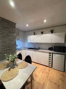a kitchen with white cabinets and a table at Casa Jaubertie - Appartement cosy et chaleureux refait à neuf - HYPER CENTRE BRIVE in Brive-la-Gaillarde
