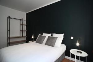a bedroom with a white bed with a black wall at Sognu di Matteu - Bel appartement entièrement climatisé - vue mer, vieux port Bastia in Bastia