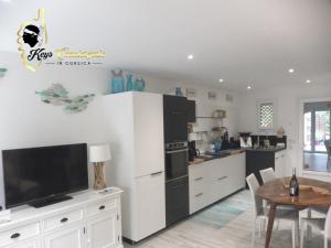 a kitchen with a white refrigerator and a table at Villa Bleu de Mer - Village Balnéaire San Cyprianu in Lecci