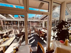 ein Restaurant mit weißen Tischen und Stühlen und großen Fenstern in der Unterkunft Parkhotel Flora in Bad Grund