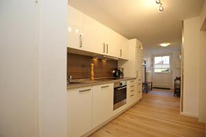 a kitchen with white cabinets and a wooden floor at Papillon Wohnung 04-3 in Boltenhagen