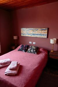 1 dormitorio con 1 cama rosa y 2 toallas en Los Abuelos Departamentos en Tafí del Valle