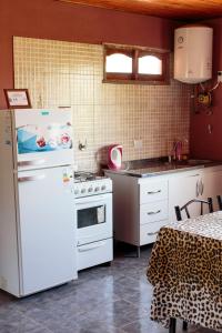 a kitchen with a white refrigerator and a stove at Los Abuelos Departamentos in Tafí del Valle