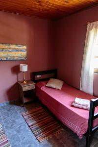 a bedroom with a bed and a table with a lamp at Los Abuelos Departamentos in Tafí del Valle