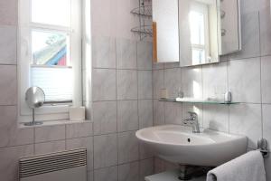 ein weißes Badezimmer mit einem Waschbecken und einem Spiegel in der Unterkunft Am Prerowstrom in Prerow