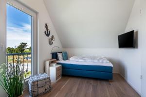 ein kleines Schlafzimmer mit einem Bett und einem Fenster in der Unterkunft NordseeResort Büsum Ferienhaus 1 Beach House in Büsum