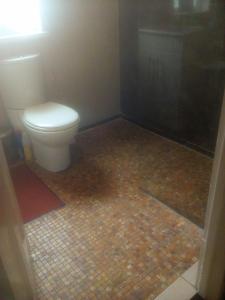 a bathroom with a toilet and a tiled floor at The Principality 2 Singles Bedroom in Cardiff