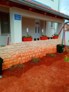 a brick wall in front of a house with plants at Apartman Josipa in Peroj