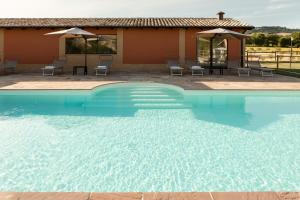 a swimming pool with chairs and a house at Agriturismo Casale San Lorenzo in San Lorenzo in Campo