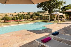 a swimming pool with two chairs and an umbrella at Agriturismo Casale San Lorenzo in San Lorenzo in Campo