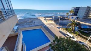 - une grande piscine bleue dans un bâtiment à côté de l'océan dans l'établissement Balcon al mar, à Bellreguart