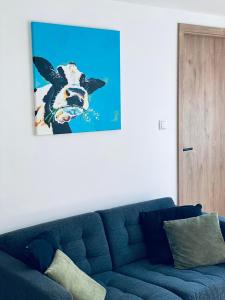 um sofá azul numa sala com uma imagem de uma vaca em Little Marguerite em Houffalize