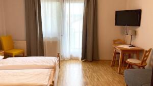 a bedroom with a bed and a desk and a television at Zöchbauer Gästehaus - Hotel Garni in Kapelln