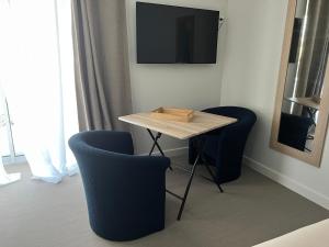 mesa con 2 sillas y TV en la pared en Chambre privatisée L’Ermitage vue sur la mayenne en Château-Gontier