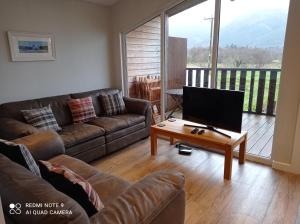 un soggiorno con divano e tavolo con TV di Glencoe view lodge a Glencoe