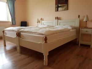 a white bed in a bedroom with a wooden floor at Connemara Haven Bed and Breakfast in Oughterard
