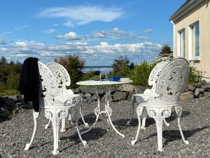 três cadeiras brancas e uma mesa num pátio em Connemara Haven Bed and Breakfast em Oughterard