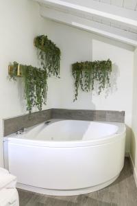 Jardines Villaverde في Villaverde Pontones: حوض استحمام أبيض مع نباتات خضراء على الحائط