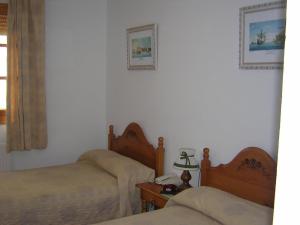 1 dormitorio con 2 camas y una lámpara en una mesa en Hostal Restaurante La Muralla, en Cañete