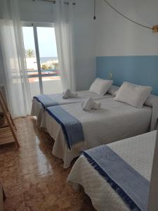 two beds in a bedroom with a view of the ocean at H El Palmeral Playa in Mojácar