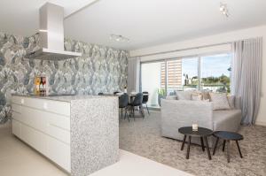 eine Küche und ein Wohnzimmer mit einem Sofa und einem Tisch in der Unterkunft Green Apartment - Luxurious & Pool & Garden & Playground & Garage in Albufeira