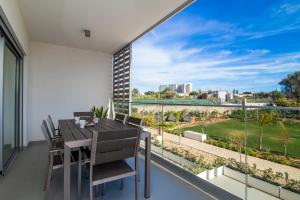 einen Balkon mit einem Tisch und Stühlen sowie einem großen Fenster in der Unterkunft Green Apartment - Luxurious & Pool & Garden & Playground & Garage in Albufeira