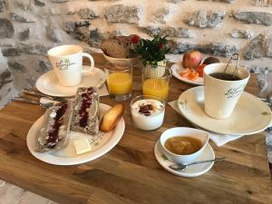 a wooden table with plates of food and cups of coffee at Chambre LA LONGERE in Treffort