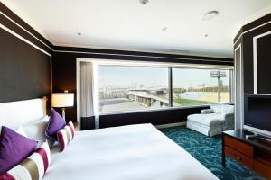 東京にあるホテルアラマンダ青山の大きなベッドと大きな窓が備わるホテルルームです。