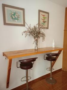 una mesa con dos taburetes y un jarrón con flores en Pensión Argüelles, en Ribadesella