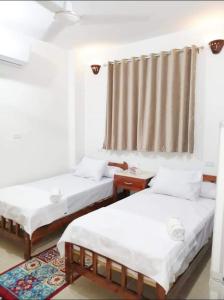 two twin beds in a room with a window at The Magic of Luxor private studio apartment on the rooftop in Luxor