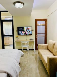 ein Schlafzimmer mit einem Bett, einem Schreibtisch und einem Sofa in der Unterkunft Dala Studio - Denis Pritt Road in Nairobi